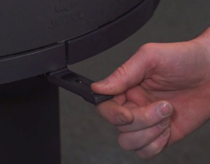 Hånd som justerer luftventil på Jøtul vedovn