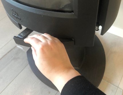 Hånd åpner døren til vedovnen forsiktig