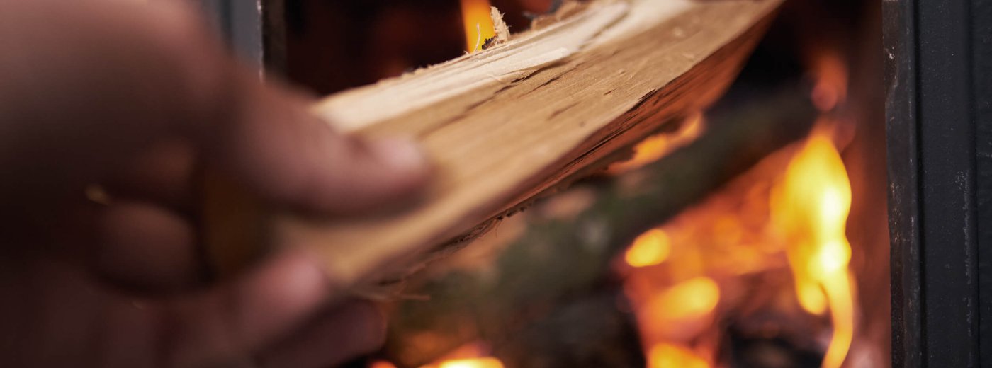 Hånd som legger ved i peisen
